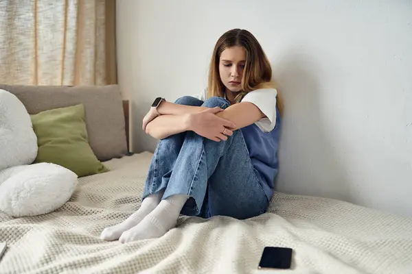 A young girl sits on her bed wrapped in thought, surrounded by the comfort of home. — Stock Photo