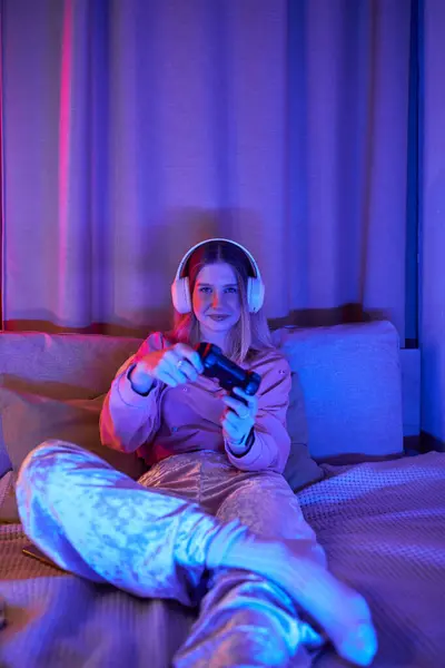 Un'adolescente si gode la sua sessione di gioco in una stanza accogliente e moderna illuminata da luci serali. — Foto stock