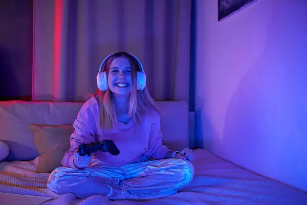 Una ragazza adolescente allegra gode di gioco nella sua elegante stanza, illuminata da luci colorate. — Foto stock