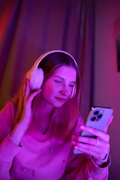A pretty teenage girl immersed in music while scrolling on her phone during the evening. — Stock Photo