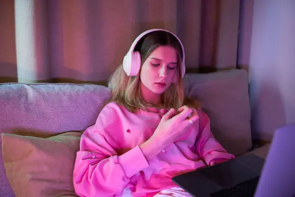 A teenage girl relaxes in her contemporary room, lost in thoughts while wearing headphones. — Stock Photo