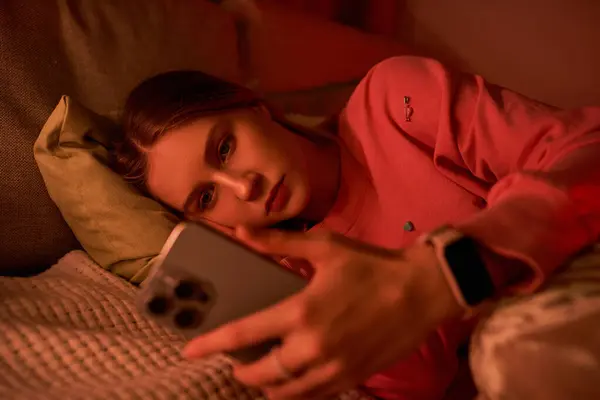 Uma menina relaxa em seu quarto moderno, imerso em seu telefone durante uma noite aconchegante. — Fotografia de Stock