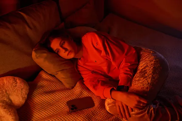A pretty teenage girl relaxes on her bed, lost in thought during the evening hours. — Stock Photo