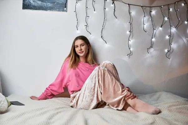 A teenage girl relaxes on her bed, enjoying a warm evening in her modern room. — Stock Photo