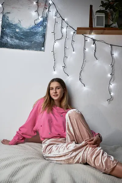 Una adolescente se relaja en su elegante habitación decorada con luces de hadas durante la noche. — Stock Photo