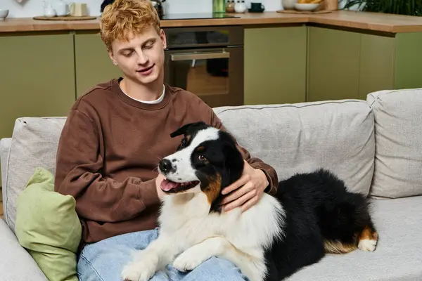 A young man enjoys quality time with his adorable Australian Shepherd in a modern apartment. — Stock Photo