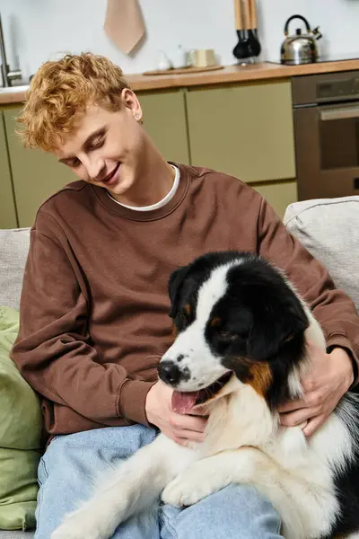 A young man with red hair shares a joyful moment with his Australian Shepherd in their modern home. — Stock Photo