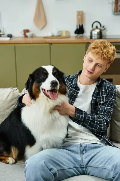 Inside a stylish apartment, a young redhead man shares a joyful moment with his Australian Shepherd. — Stock Photo