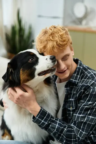 A young redhead man shares a loving moment with his Australian Shepherd dog in a modern home. — Stock Photo
