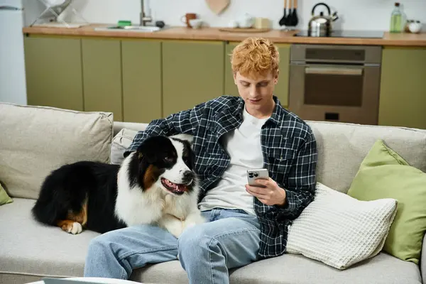 A young man with red hair enjoys quality time with his Australian Shepherd at home. — Stock Photo