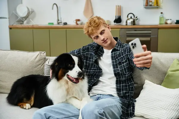 Young man captures a playful selfie with his adorable Australian Shepherd in a stylish home. — Stock Photo