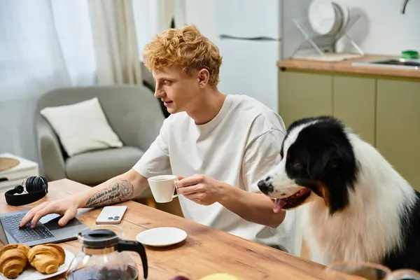 A redhead man relaxes at home, sipping coffee while his dog sits nearby, creating a cozy atmosphere. — Stock Photo