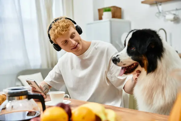 Redhead man relaxes with his Australian Shepherd dog in a stylish apartment, sharing moments. — Stock Photo