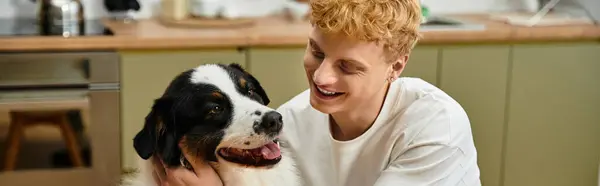 A young redhead man joyfully interacts with his Australian Shepherd in their stylish home, banner — Stock Photo