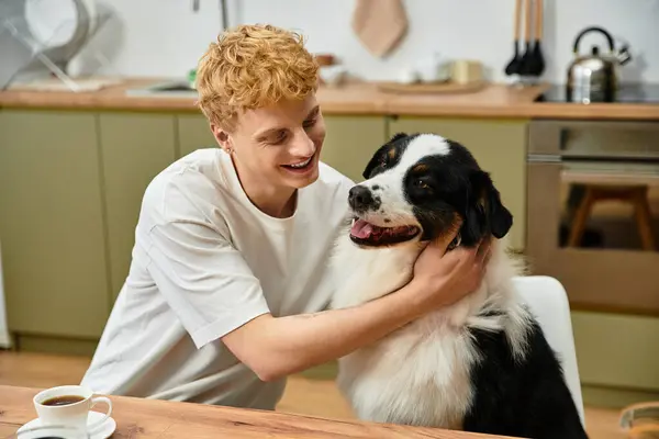 In a modern apartment, a young man lovingly interacts with his cheerful Australian Shepherd dog. — Stock Photo