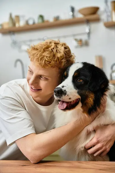 In a modern apartment, a redhead man relaxes and bonds with his cute Australian Shepherd dog. — Stock Photo