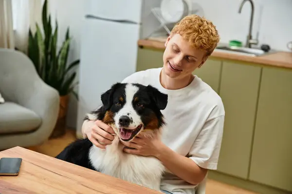 A young redhead man enjoys quality time with his playful Australian Shepherd at home. — Stock Photo