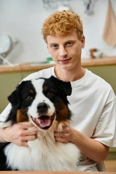 Um jovem com cabelo vermelho interage com seu adorável cão pastor australiano em casa. — Fotografia de Stock