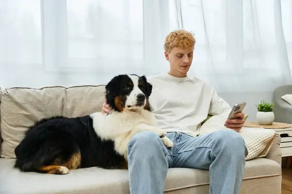 Relaxing at home, a young redhead man spends time with his adorable Australian Shepherd companion. — Stock Photo