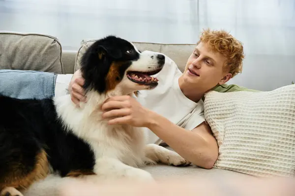 A cheerful redhead man interacts lovingly with his sweet Australian Shepherd dog at home. — Stock Photo
