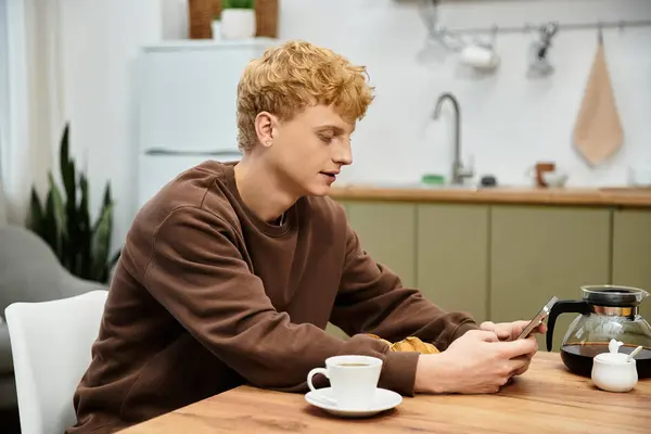 A young redhead man enjoys a casual morning while checking his phone at home. — Stock Photo