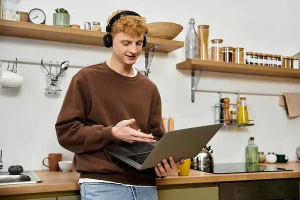 Young man in casual attire interacts with his laptop in a stylish apartment setup. — Stock Photo