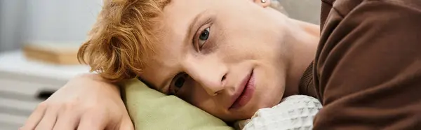 A young man with red hair lounges casually in his stylish apartment, embracing comfort, banner — Stock Photo