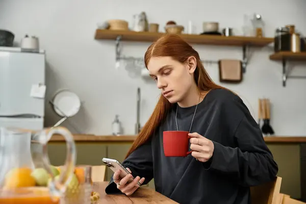 Relaxed young adult sips coffee while browsing on his phone in a chic living space. — Stock Photo