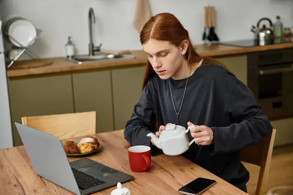 Momentos casuales se desarrollan como un joven sirve té mientras saborea el desayuno en casa. - foto de stock