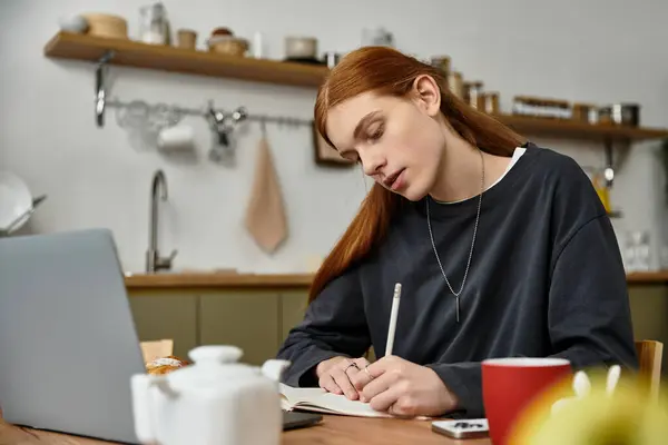 In un appartamento chic, un giovane con i capelli lunghi scrive in un quaderno, rivelando la sua creatività.. — Foto stock