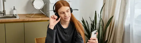 A young man enjoys a moment of connection while relaxing in his modern apartment, banner — Stock Photo