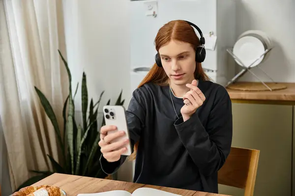 Young man with long hair listens to music while checking his phone in his modern apartment. — Stock Photo