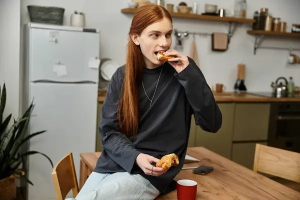Um jovem elegante come casualmente enquanto relaxa em seu apartamento moderno. — Fotografia de Stock