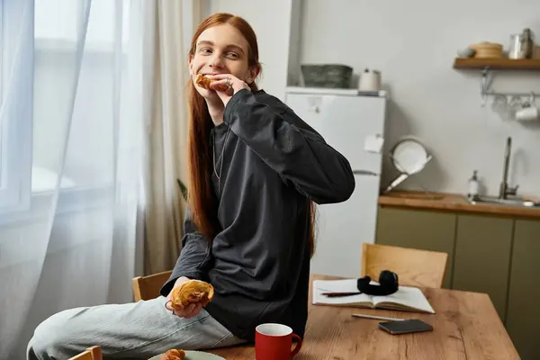 Casual jovem com cabelos longos comendo feliz café da manhã em seu elegante apartamento. — Fotografia de Stock