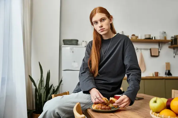 Momento de estilo de vida casual apresenta um jovem com cabelos longos sentado em sua mesa de cozinha. — Fotografia de Stock