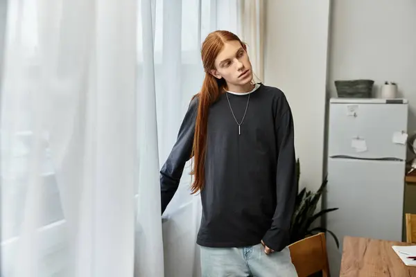 Stylish young adult relaxed indoors, admiring the view from his modern apartment window. — Stock Photo
