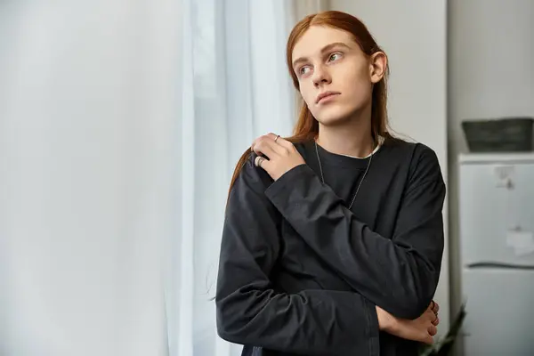 Casual scene featuring a young guy with long hair lost in thought in his stylish apartment. — Stock Photo