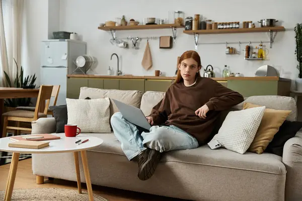 Relaxing in his stylish apartment, a young redhead man works on his laptop while dressed casually. — Stock Photo