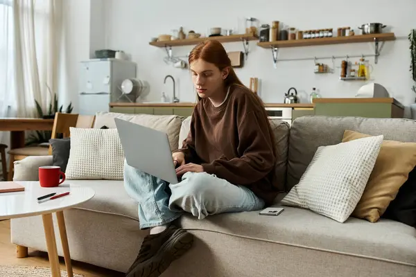 Ein hübscher Rotschopf entspannt sich in seinem lässigen Sweatshirt, während er zu Hause online arbeitet. — Stockfoto