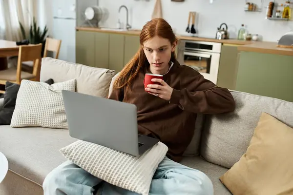 A good looking young man with long red hair relaxes at home while sipping coffee. — Stock Photo
