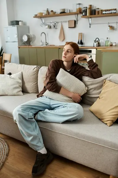 Relaxing in a cozy apartment, the young man reflects while seated on the couch. — Stock Photo