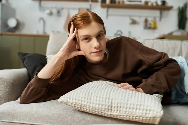 Comfortably lounging on the sofa, a young redhead man enjoys his cozy apartment life. — Stock Photo