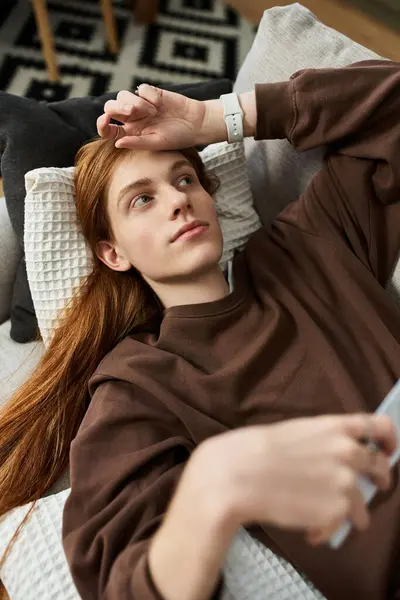 A stylish young man lounges comfortably on a sofa, enjoying a moment of relaxation in his apartment. — Stock Photo