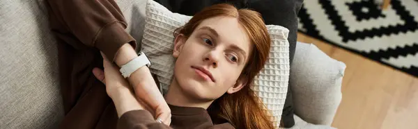 A young redhead man relaxes in his cozy apartment, dressed in a casual sweatshirt, banner — Stock Photo