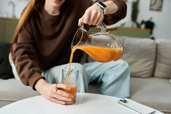 Momento brillante y casual como un joven con estilo vierte jugo en su acogedora casa. - foto de stock