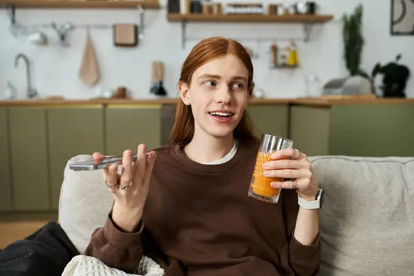 Bright and inviting atmosphere as a young redhead relaxes with a drink at home. — Stock Photo