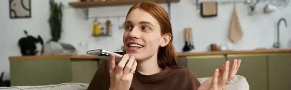 Un joven con el pelo largo y rojo disfruta de una animada conversación en su acogedor apartamento, pancarta — Stock Photo