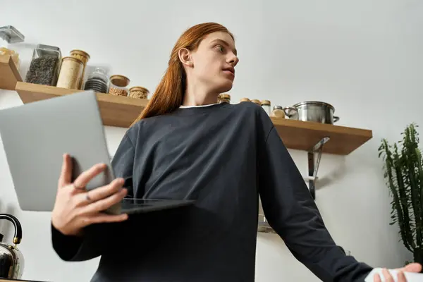 A young redhead guy with long hair relaxes at home in casual attire, enjoying his modern space. — Stock Photo