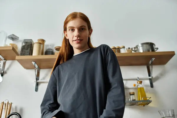 A good looking young man with long red hair relaxes in his stylish sweatshirt at home. — Stock Photo