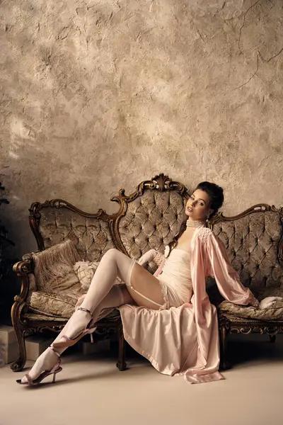 A beautiful young woman relaxes elegantly on a vintage sofa, exuding a mystical aura. — Stock Photo